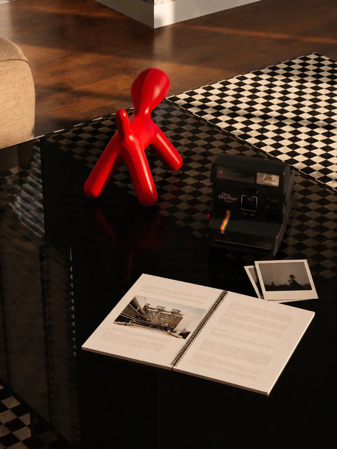 Polaroid camera, book and red object on coffee table